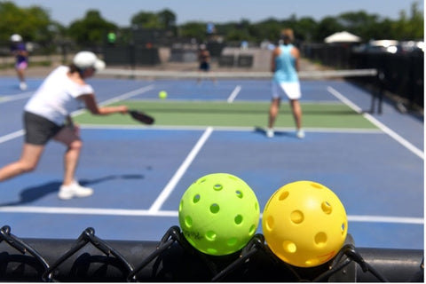 Pickleballs upclose with a match going on in the background