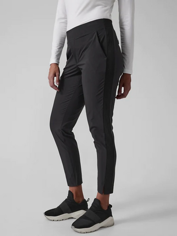 Woman in black athletic pants with grey background and white shirt